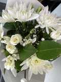 Exceptional White bouquet with layered white blooms, creamy rosebuds and green foliage in white wrapping